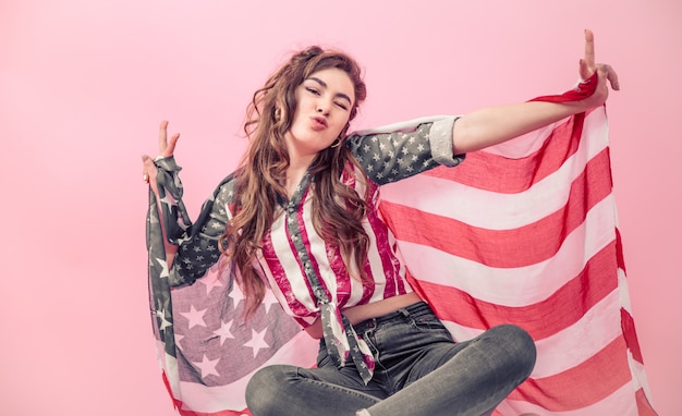 Foto gratuita niña patriótica con la bandera de américa en una pared de color