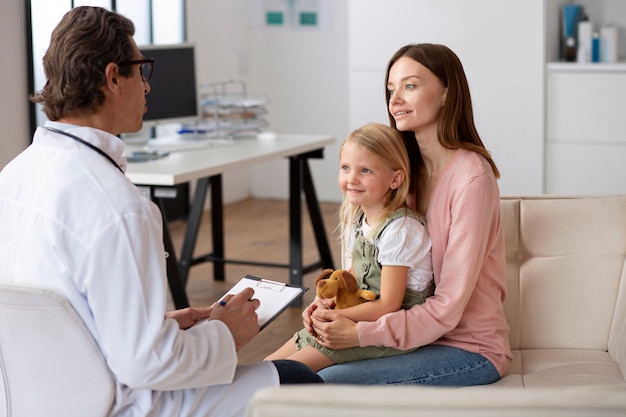 Niña en el pediatra para una consulta con su médico y su madre