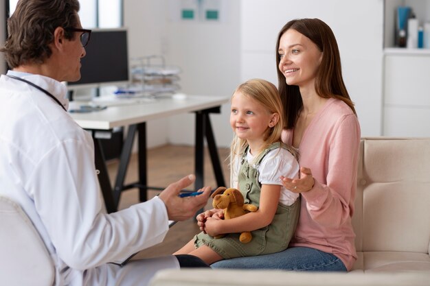Niña en el pediatra para una consulta con su médico y su madre