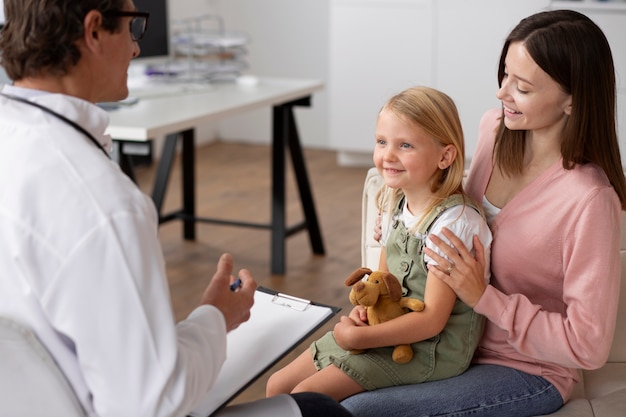 Niña en el pediatra para una consulta con su médico y su madre