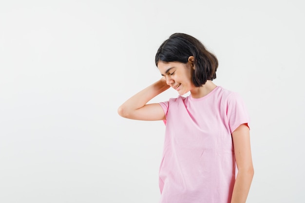 Niña pensando con los ojos cerrados en camiseta rosa y mirando pacífica, vista frontal.