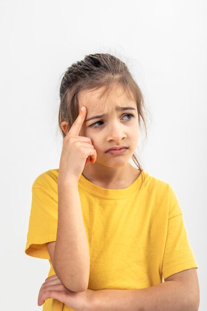 Niña pensando sosteniendo el dedo en la sien aislado sobre fondo blanco.