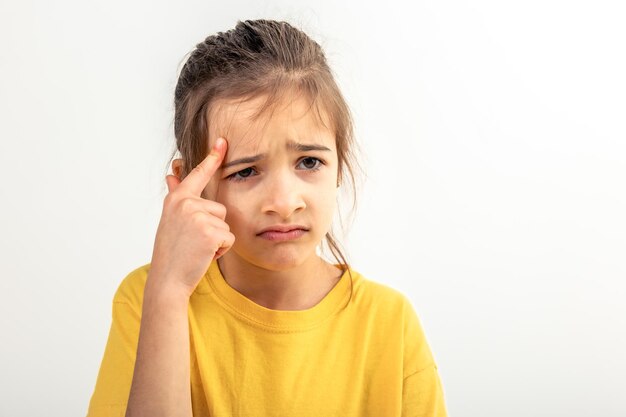 Niña pensando sosteniendo el dedo en el templo aislado en fondo blanco