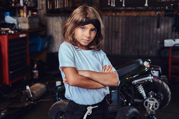 Niña pensativa está posando para el fotógrafo cruzó las manos en el servicio de auto.