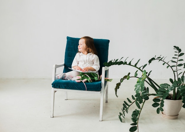 Niña pensativa sentada en sillón