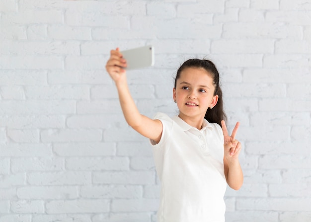 Niña pequeña adorable haciéndose un selfie