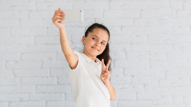 Niña pequeña adorable haciéndose un selfie