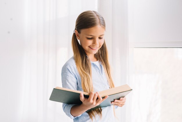 Niña pequeña adorable leyendo un libro