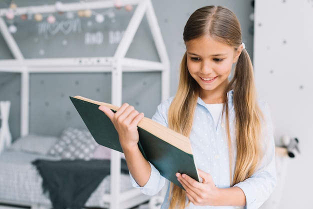 Niña pequeña adorable leyendo un libro