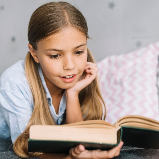 Niña pequeña adorable leyendo un libro