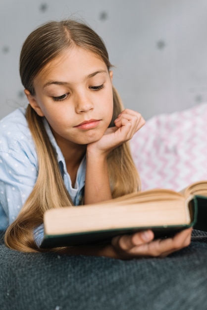 Niña pequeña adorable leyendo un libro