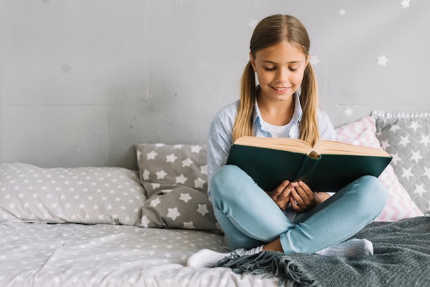 Niña pequeña adorable leyendo un libro