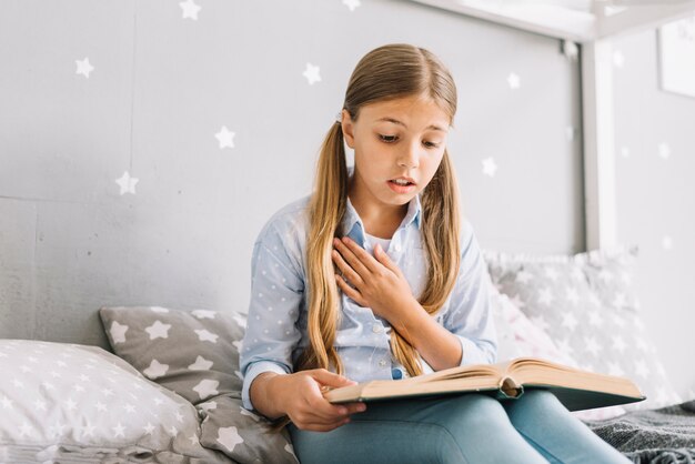 Niña pequeña adorable leyendo un libro