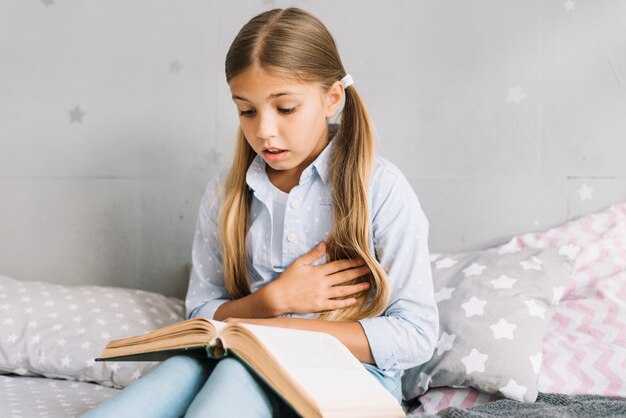 Niña pequeña adorable leyendo un libro