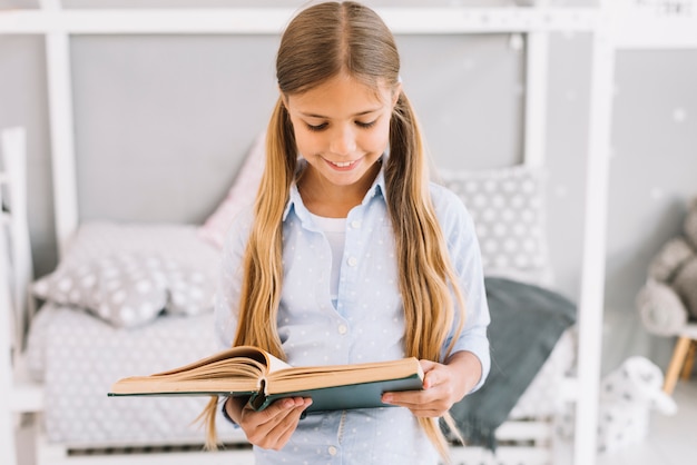 Niña pequeña adorable leyendo un libro