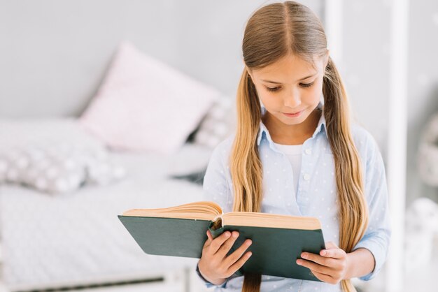 Niña pequeña adorable leyendo un libro