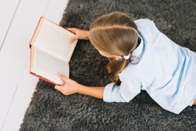 Niña pequeña adorable leyendo un libro