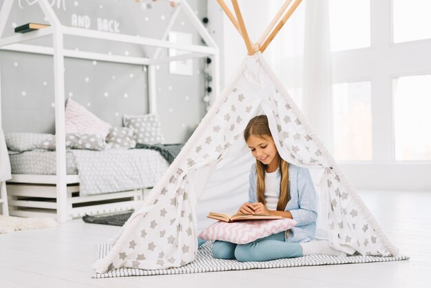 Niña pequeña adorable leyendo un libro