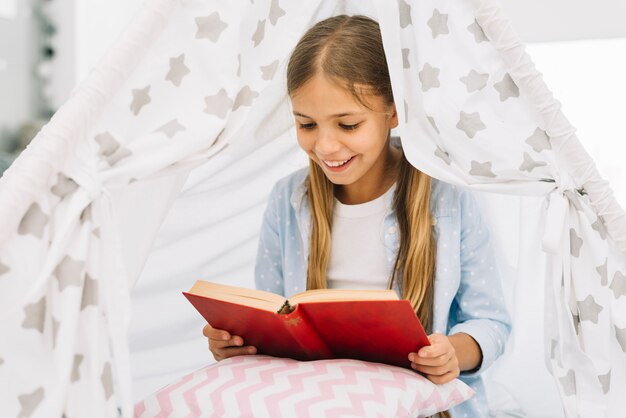 Niña pequeña adorable leyendo un libro