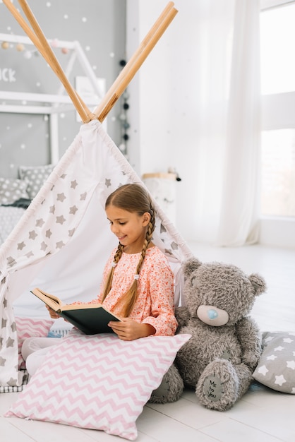 Niña pequeña adorable leyendo un libro