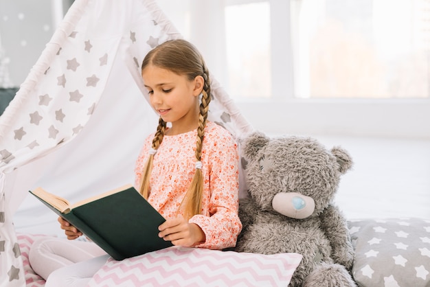 Foto gratuita niña pequeña adorable leyendo un libro