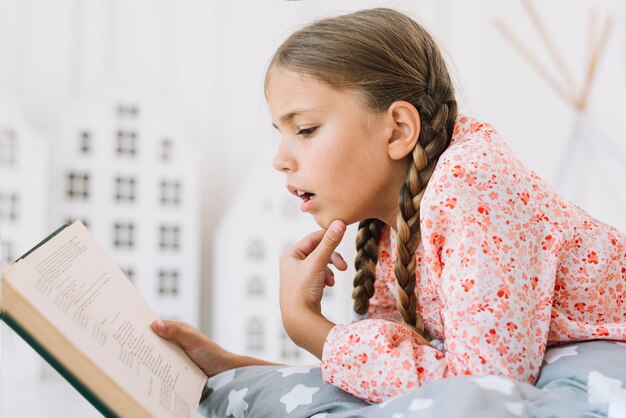 Niña pequeña adorable leyendo un libro