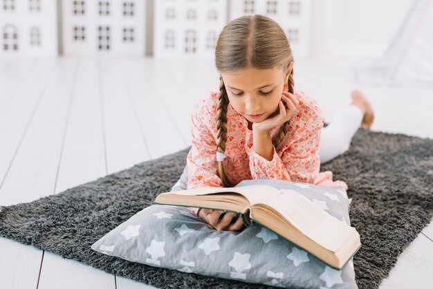 Niña pequeña adorable leyendo un libro