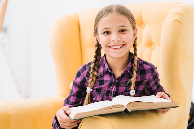 Niña pequeña adorable leyendo un libro