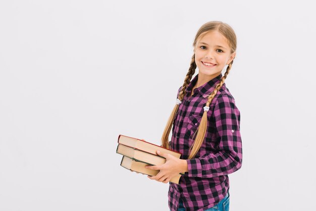 Niña pequeña adorable posando con libros