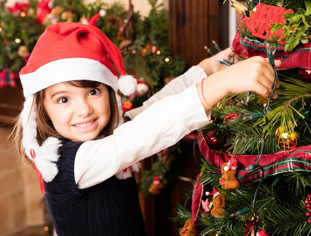 Niña pequeña colocando las luces en el árbol