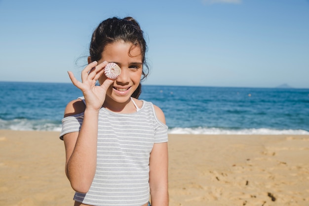 Niña pequeña divirtiéndose con una caracola