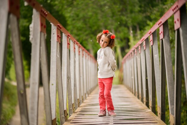 Niña pequeña encantadora cruzando un puente