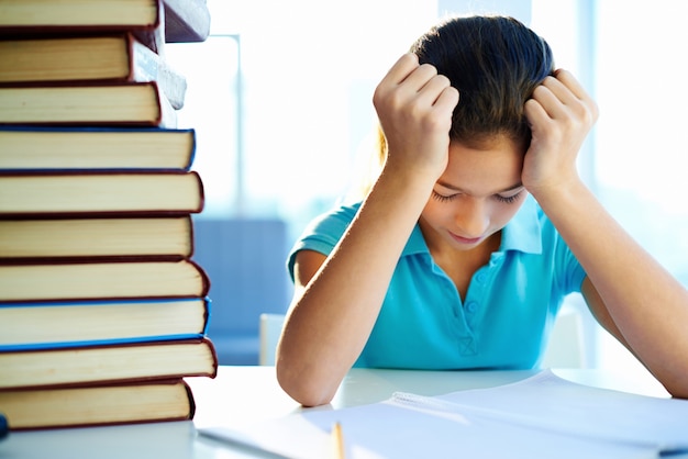 Foto gratuita niña pequeña estudiando concentrada