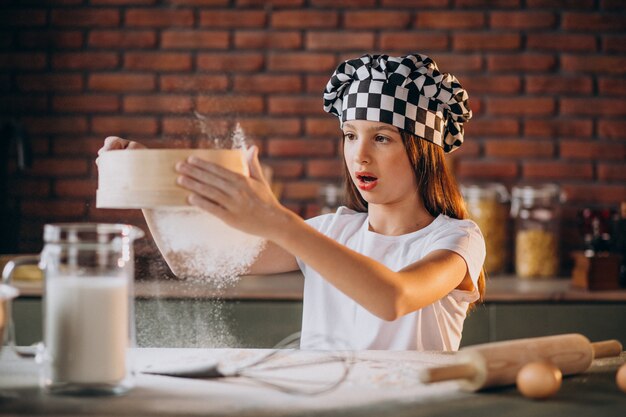 Niña pequeña hornear pasteles en la cocina para el desayuno