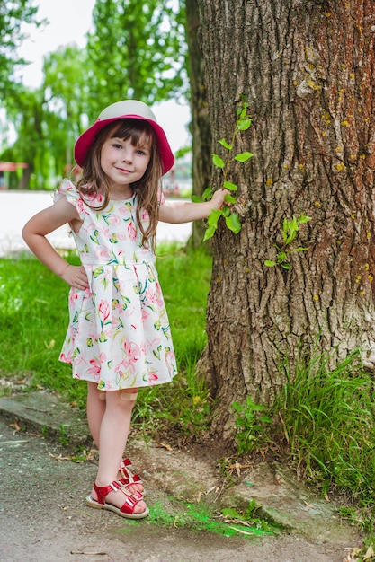 Niña pequeña con una mano apoyada en un árbol