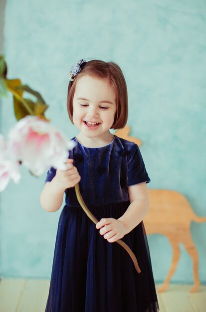 La niña pequeña mantiene las flores en la habitación