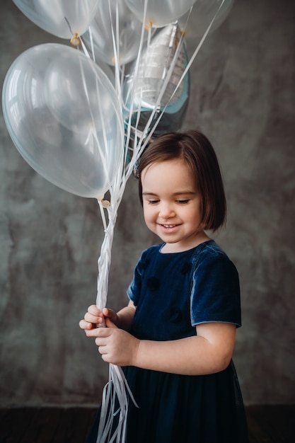 La niña pequeña mantiene los globos en la habitación