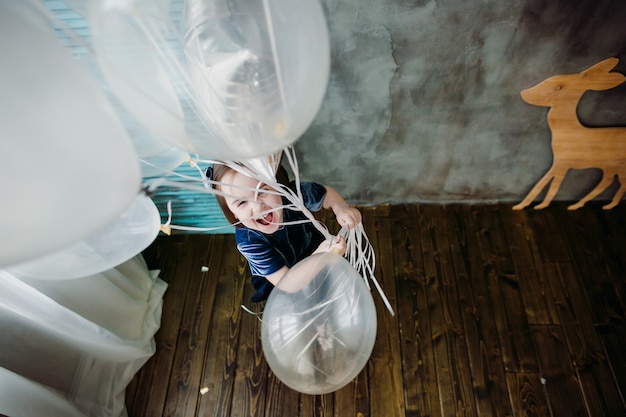 La niña pequeña mantiene globos en la habitación