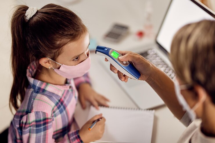 Foto gratuito niña pequeña midiendo su temperatura con termómetro infrarrojo