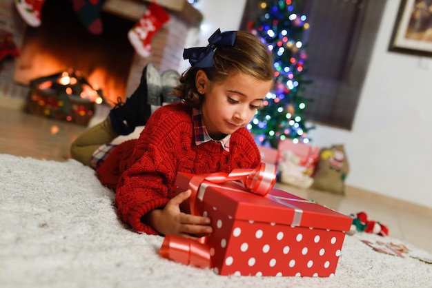 Niña pequeña mirando un regalo rojo