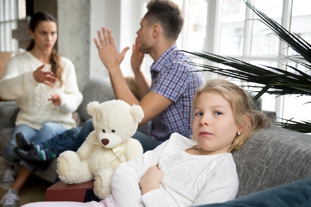 Niña pequeña molesta deprimida con padres argumentos o divorcio