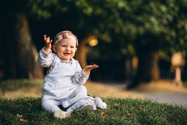 Niña pequeña que se sienta en hierba en parque