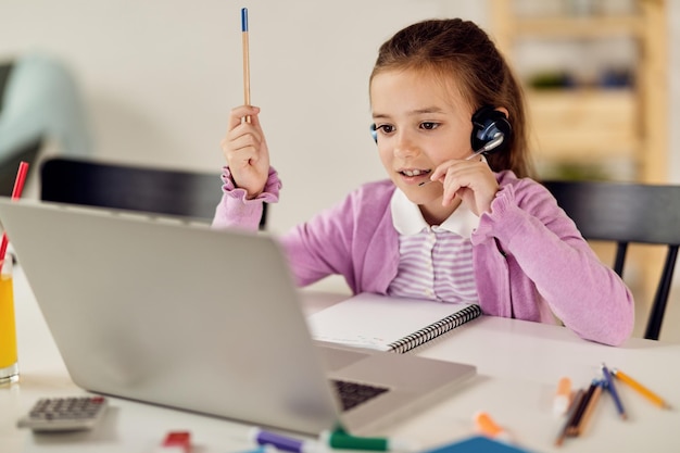 Foto gratuita niña pequeña que tiene una videollamada en una computadora portátil mientras estudia en casa durante la epidemia de virus