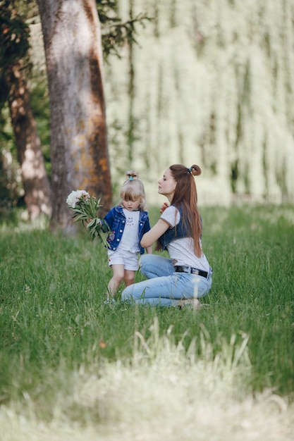 Niña pequeña con un ramo de flores blancas con su madre al lado