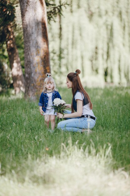 Niña pequeña con un ramo de flores blancas con su madre al lado