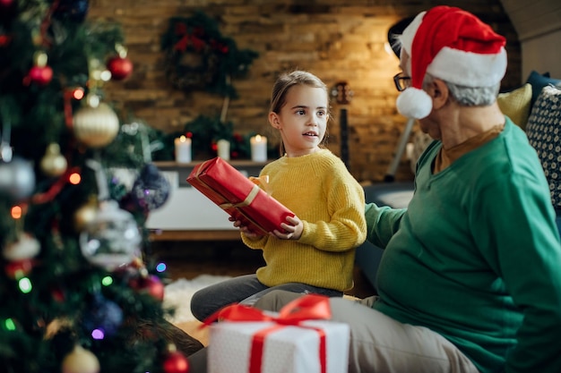 Niña pequeña recibiendo un regalo del abuelo en Navidad