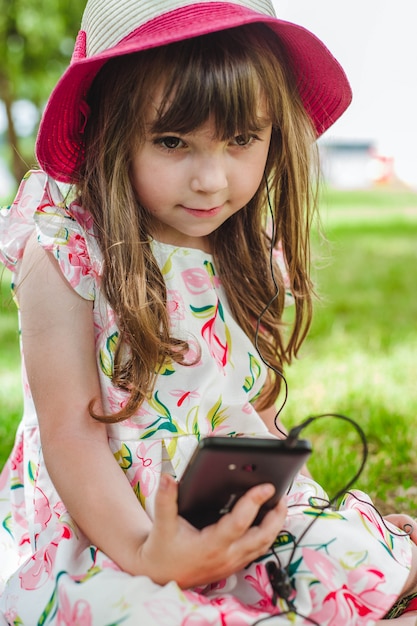 Niña pequeña sentada en el suelo con un teléfono inteligente