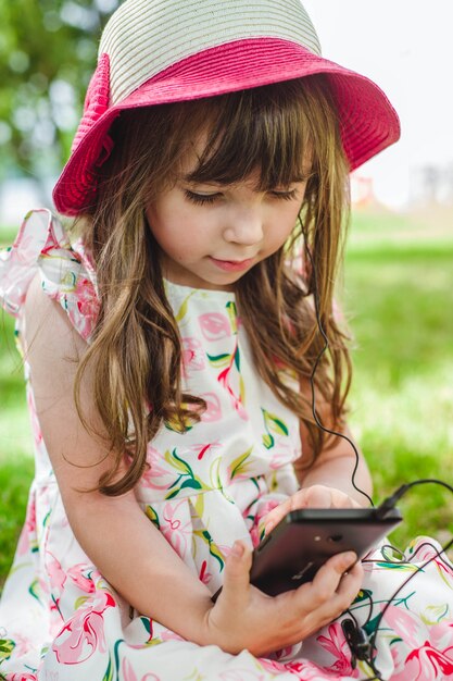 Niña pequeña sentada en el suelo con un teléfono inteligente