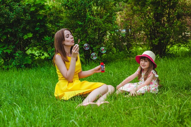 Niña pequeña sonriendo mientras su madre hace pompas de jabón