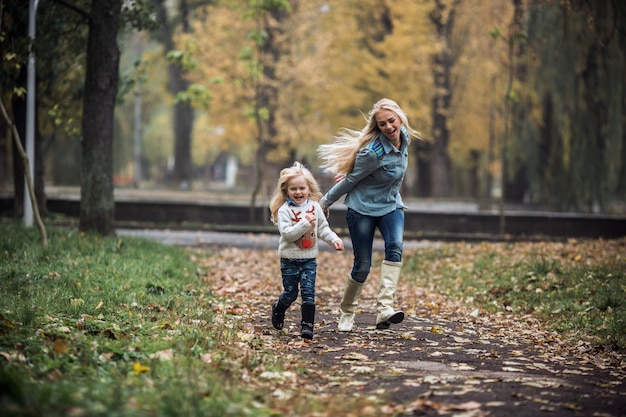 Niña pequeña sonriente jugando con su madre en el parque